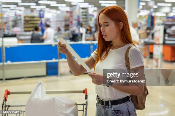 surprised woman looks at receipt total with food in mall - starving woman stock pictures, royalty-free photos & images