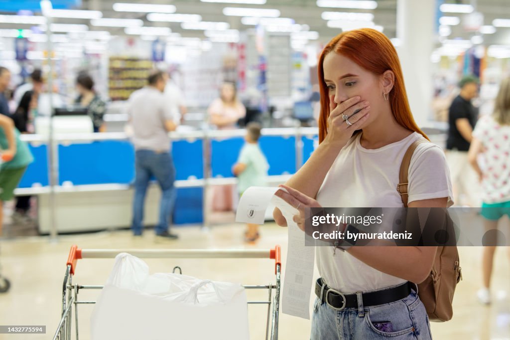 Surprised woman looks at receipt total with food in mall