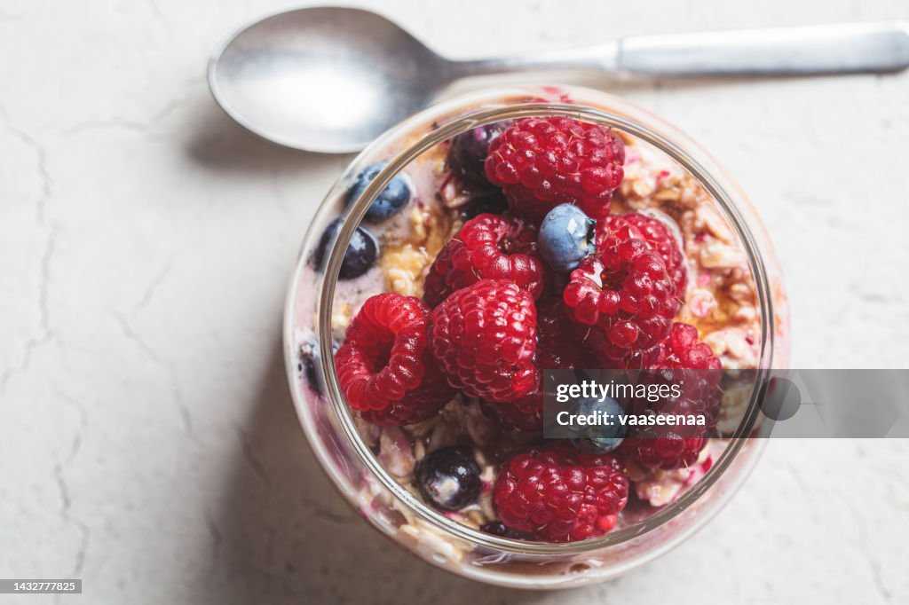 Overnight oatmeal with berry, peanut butter and maple syrup in jar. Healthy breakfast concept.