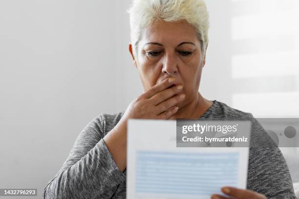 mature woman checking her energy bills at home - electrical shock stockfoto's en -beelden