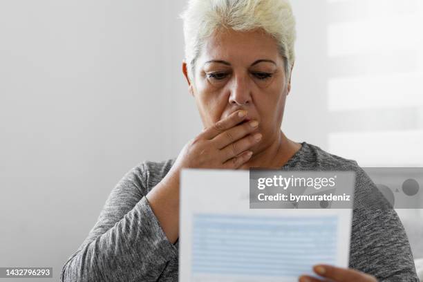mature woman checking her energy bills at home - electrical shock stock pictures, royalty-free photos & images
