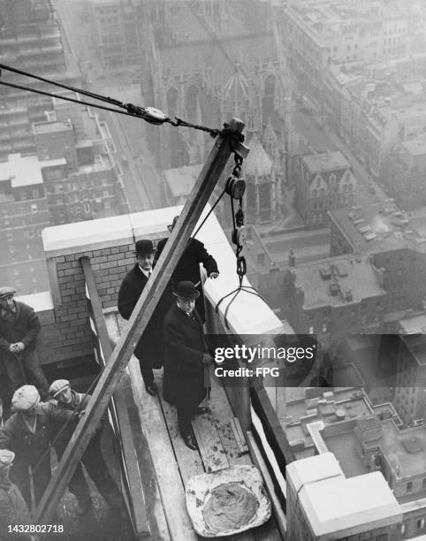 High angle view of American banker, businessman and financier Charles Hayden , holding a ceremonial gold trowel, American hotelier Lucius M Boomer ,...