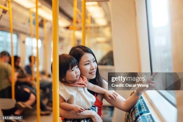 young asian mother and her toddler daughter enjoy traveling by train - baby pointing stockfoto's en -beelden