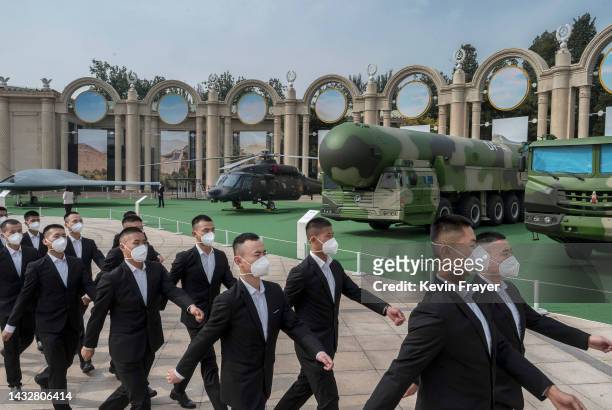 Guards walk by a display of military hardware at an exhibition highlighting Chinese President Xi Jinping's years as leader, as part of the upcoming...
