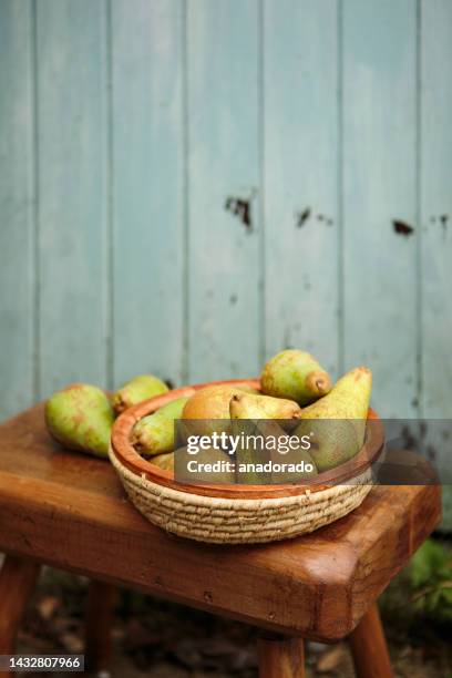 close-up of a basket of pears on a wooden stool in the garden - pears stock-fotos und bilder