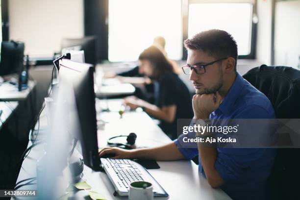 computer programmer working on new software program. - man in office concentrating stock pictures, royalty-free photos & images