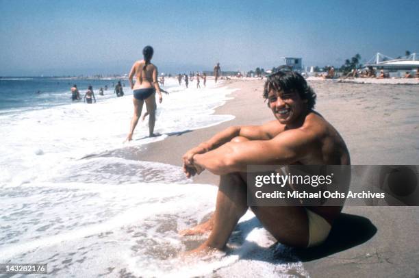 Austrian Bodybuilder Arnold Schwarzenegger sits in the surf on Venice Beach in August 1977 in Los Angeles, California.