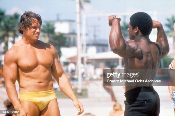 Austrian Bodybuilder Arnold Schwarzenegger admires another bodybuilder at Muscle Beach in Venice in August 1977 in Los Angeles, California.