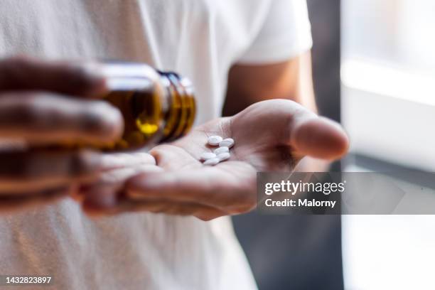 young man spilling multiple pills in his hand. - dose fotografías e imágenes de stock