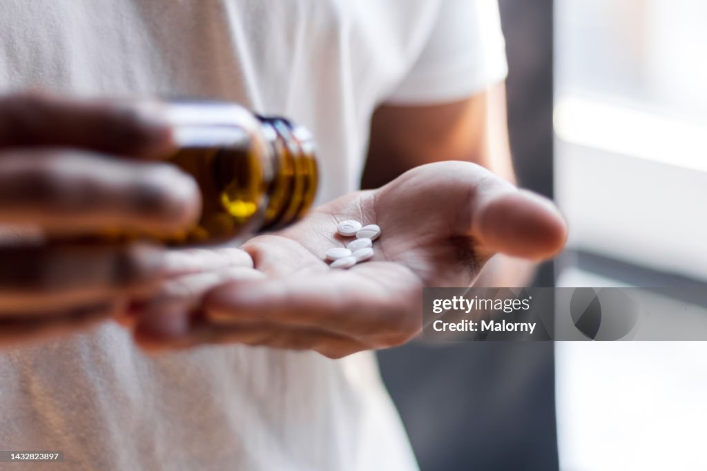 Young man spilling multiple pills in his hand.
