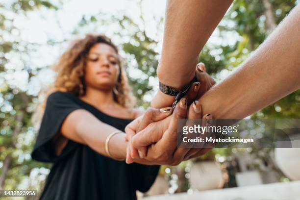 foto de dos hembras tomadas de la mano, diversidad en el color de la piel - anonymous activist network fotografías e imágenes de stock