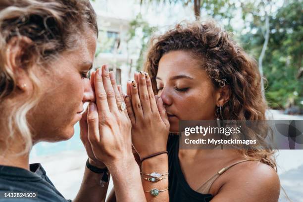 offene multirassische frauen kopf an kopf in namaste-gebetspose im freien - prayer pose greeting stock-fotos und bilder