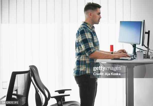 computer programmer working on new software program. - standing desk posture stock pictures, royalty-free photos & images