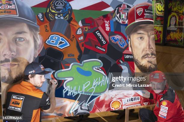 Jack Miller of Australia and Ducati Lenovo Team and Remy Gartner of Australia and Tech3 KTM Factory Racing smile and sign the artwork by Justine...