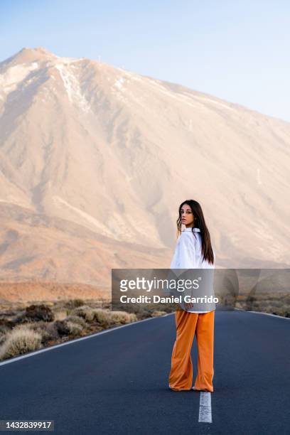 girl barefoot from the back looking at the camera in the middle of the teide road, teide national park, tenerife - young woman looking over shoulder stock pictures, royalty-free photos & images