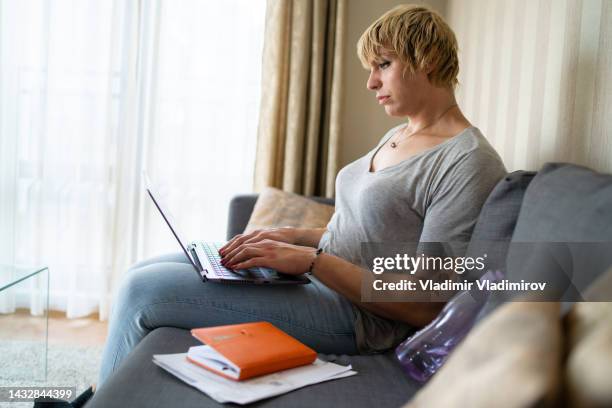 a transgender woman looking at its online banking while working on her finances - avondschool stockfoto's en -beelden
