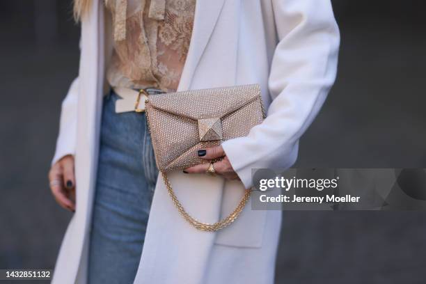Tanja Comba is seen wearing beige/gold lace blouse from Valentino, blue denim pants from Khaite, creme white long knit cardigan/coat from Roberto...