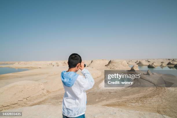 giovane ragazzo che si gode il paesaggio con un binocolo sulla collina di yardang - provincia del qinghai foto e immagini stock