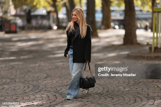 Tanja Comba is seen wearing black laced top from Dior, blue denim oversize wide leg pants from Khaite, black oversized Bottega Veneta blazer jacket,...