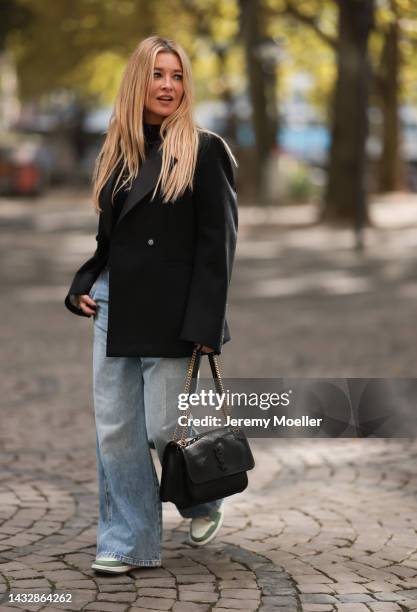 Tanja Comba is seen wearing black laced top from Dior, blue denim oversize wide leg pants from Khaite, black oversized Bottega Veneta blazer jacket,...