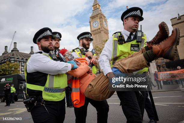 Police officers arrest an Insulate Britain protester at Parliament Square on October 12, 2022 in London, England. Two groups of environmental...