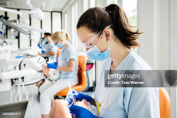 student dentist practicing surgical procedure on dummy in class - safety glasses stock-fotos und bilder