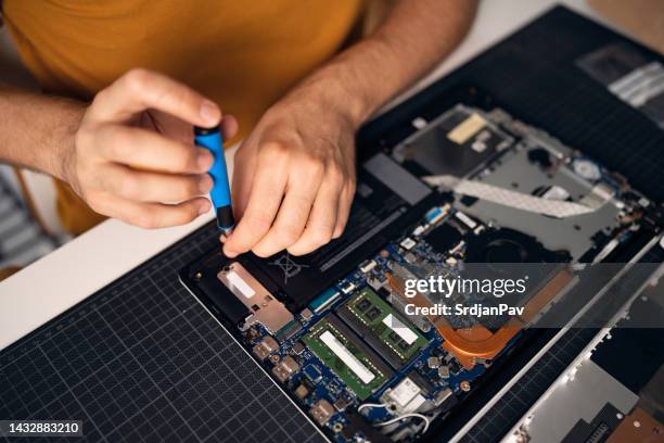 unrecognizable man with screwdriver repairing his laptop - schroevendraaier stockfoto's en -beelden