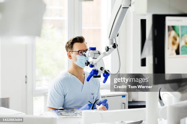 student dentist looking through magnifying scope - medische procedure stockfoto's en -beelden