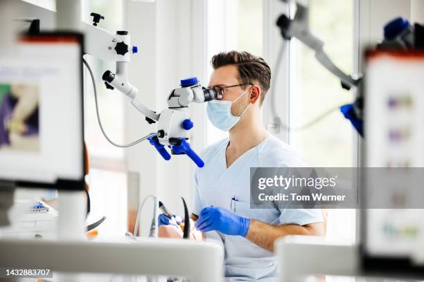 student dentist looking through scope while practicing procedure - medical instrument stock pictures, royalty-free photos & images