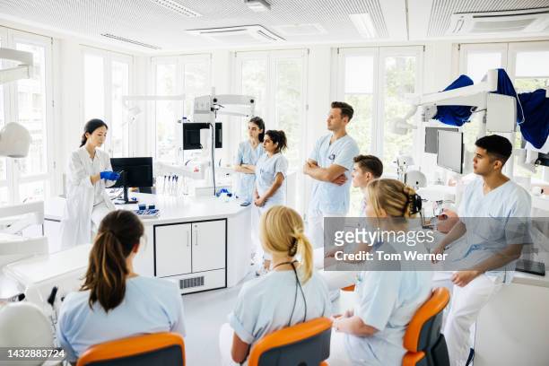 students listening to teacher talking in dental surgery - european doctor stock-fotos und bilder