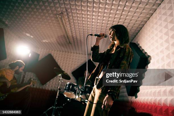 female singer, male drummer, and guitarist having a band rehearsal - modern rock stockfoto's en -beelden