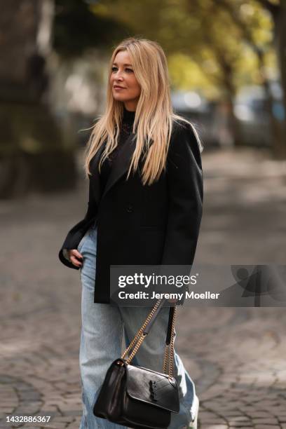 Tanja Comba is seen wearing black laced top from Dior, blue denim oversize wide leg pants from Khaite, black oversized Bottega Veneta blazer jacket,...