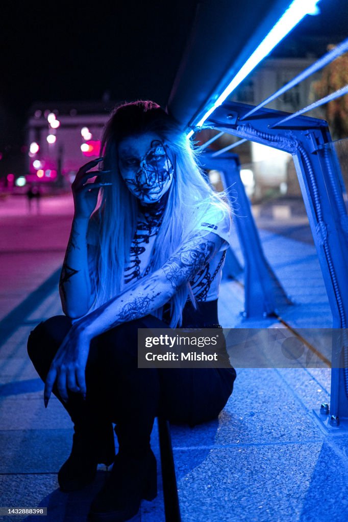 Woman with scary sceleton face painting mask and drawn tattoos on arms