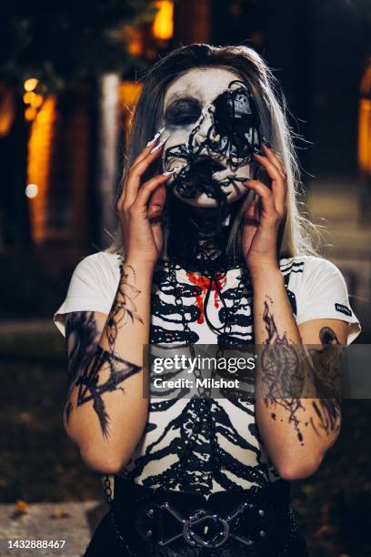 woman with scary sceleton face painting mask and drawn tattoos on arms - evil face tattoo designs stock pictures, royalty-free photos & images