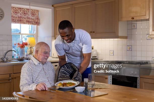 serving a hot meal to a senior man - meals on wheels stock pictures, royalty-free photos & images