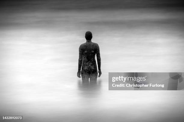 The tide goes out behind one of the statues at Antony Gormley's art installation 'Another Place' at Crosby Beach on October 12, 2022 in Liverpool,...