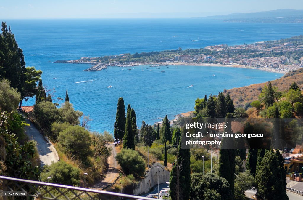 Spectacular view of the blue waters of the Ionic Sea, the Naxos coastline and the seaside resort of Giardini Naxos, Taormina, Sicily, Italy