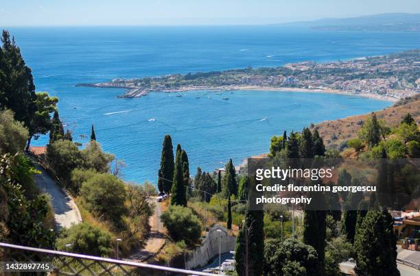 spectacular view of the blue waters of the ionic sea, the naxos coastline and the seaside resort of giardini naxos, taormina, sicily, italy - giardini naxos stock-fotos und bilder