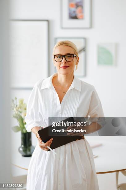 portrait of smiling business woman using a digital tablet at work - teacher looking at camera stock pictures, royalty-free photos & images