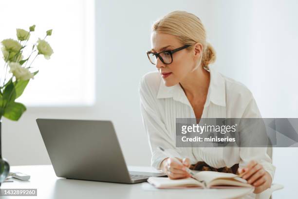 beautiful business woman using a laptop computer at work - desk woman glasses stock pictures, royalty-free photos & images