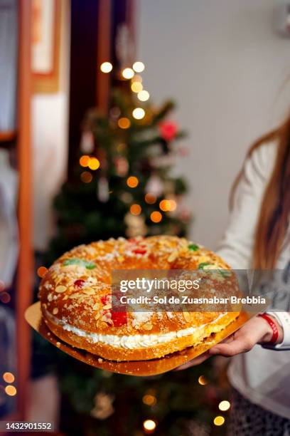 close-up of hands holding a roscón de reyes - rosca de reyes fotografías e imágenes de stock