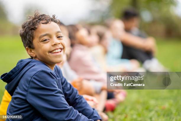 young boy sitting with friends - pre adolescent child stock pictures, royalty-free photos & images