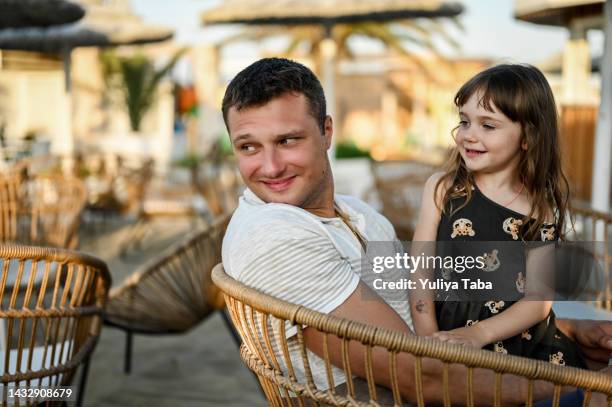 father and daughter on summer holidays. happy father and his adorable little daughter on summer cafe  cheerful family having fun in summer day at beach cafe. - happy holidays family stock pictures, royalty-free photos & images