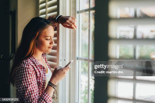 mujer en la página mensajes de texto en el teléfono inteligente - jalousie fotografías e imágenes de stock