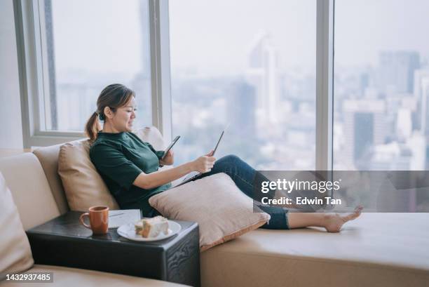 asian chinese woman with disability deformed arm checking text messages at home sitting on sofa bed - of deformed people stock pictures, royalty-free photos & images