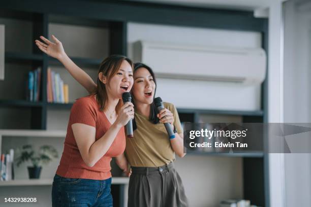 asian chinese woman with disability deformed arm singing karaoke with her friend at home - duet stock pictures, royalty-free photos & images