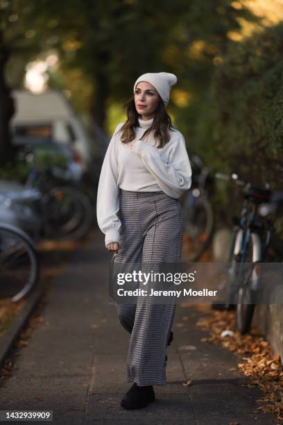 Anna Wolfers wearing a cream knit hat, cream turtleneck sweater, plaid brown trousers and black boots on October 06, 2022 in Hamburg, Germany.
