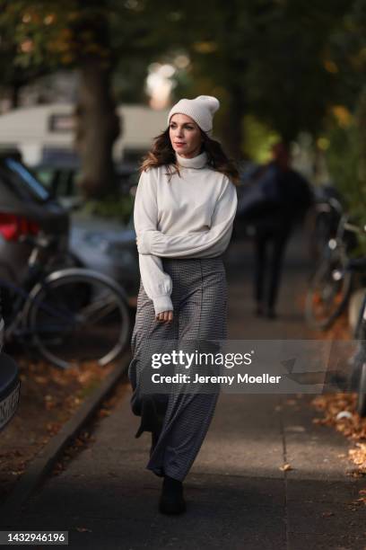 Anna Wolfers wearing a cream knit hat, cream turtleneck sweater, plaid brown trousers and black boots on October 06, 2022 in Hamburg, Germany.