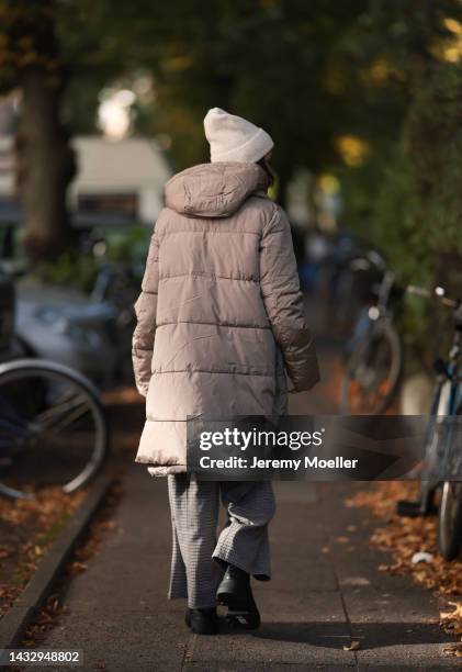 Anna Wolfers wearing a cream knit hat, cream turtleneck sweater, beige winter coat, plaid brown trousers and black boots on October 06, 2022 in...
