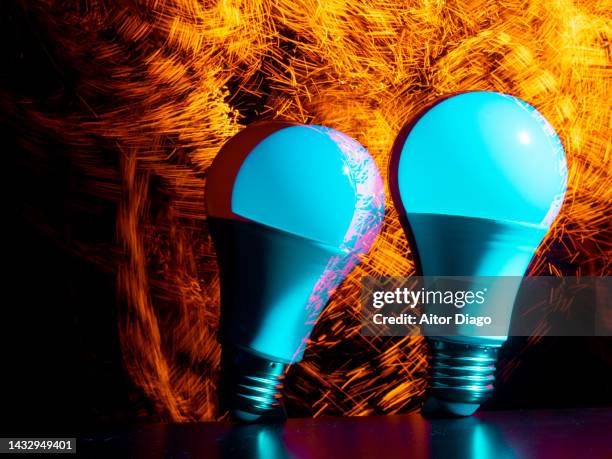 two light bulbs in movement  and fire in the background. concept of energy. - recessed lighting fotografías e imágenes de stock
